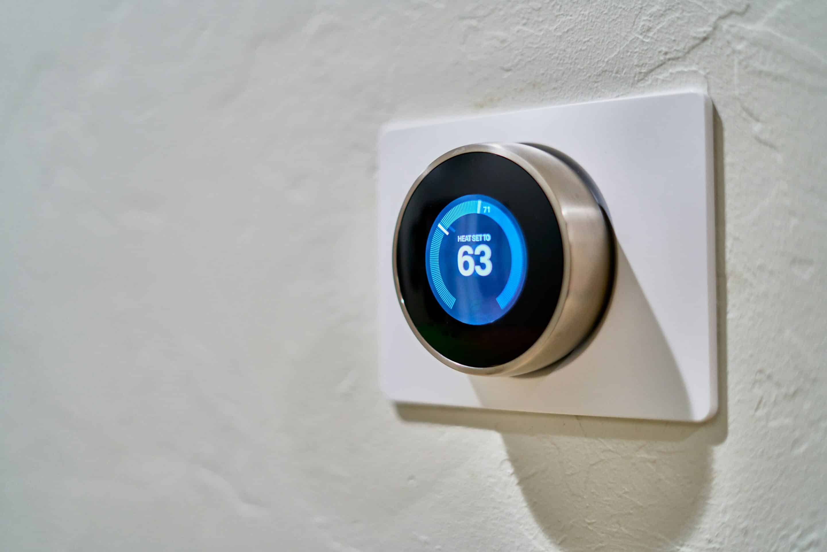 Smart thermostat mounted on wall with blue digital display